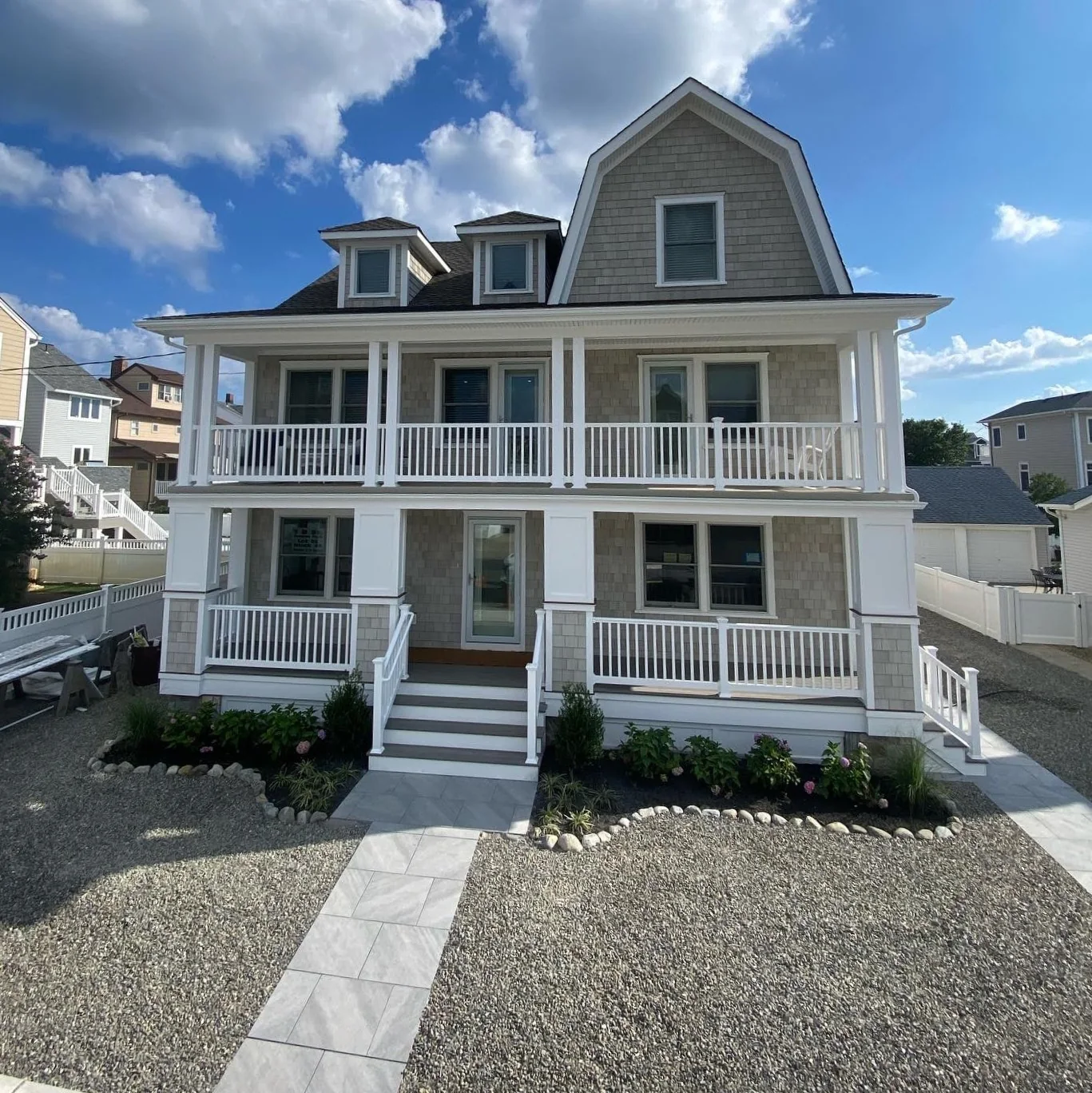 Finished coastal home front exterior with wraparound porch and white rails