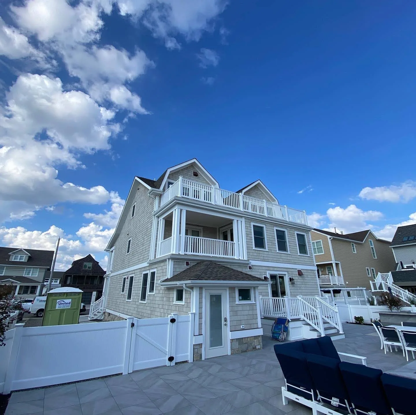 Finished coastal home rear exterior with raised decks and patio