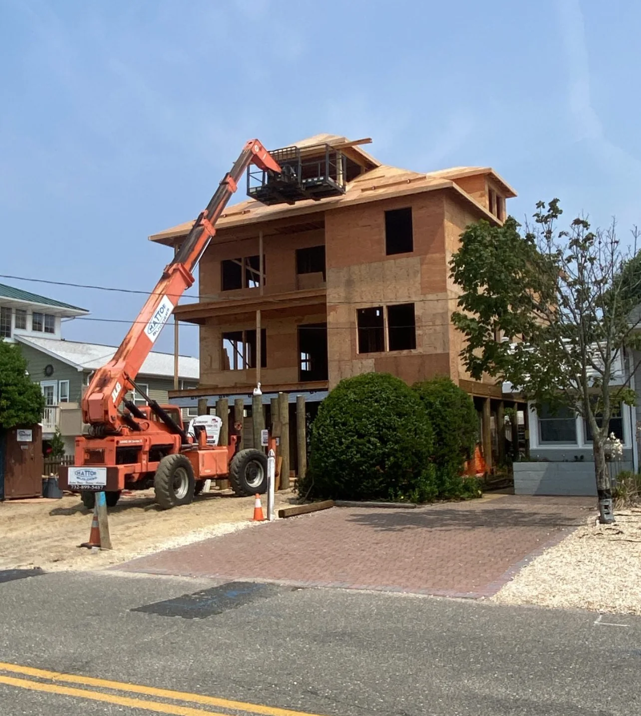 Lift staged at a raised coastal home during framing and sheathing