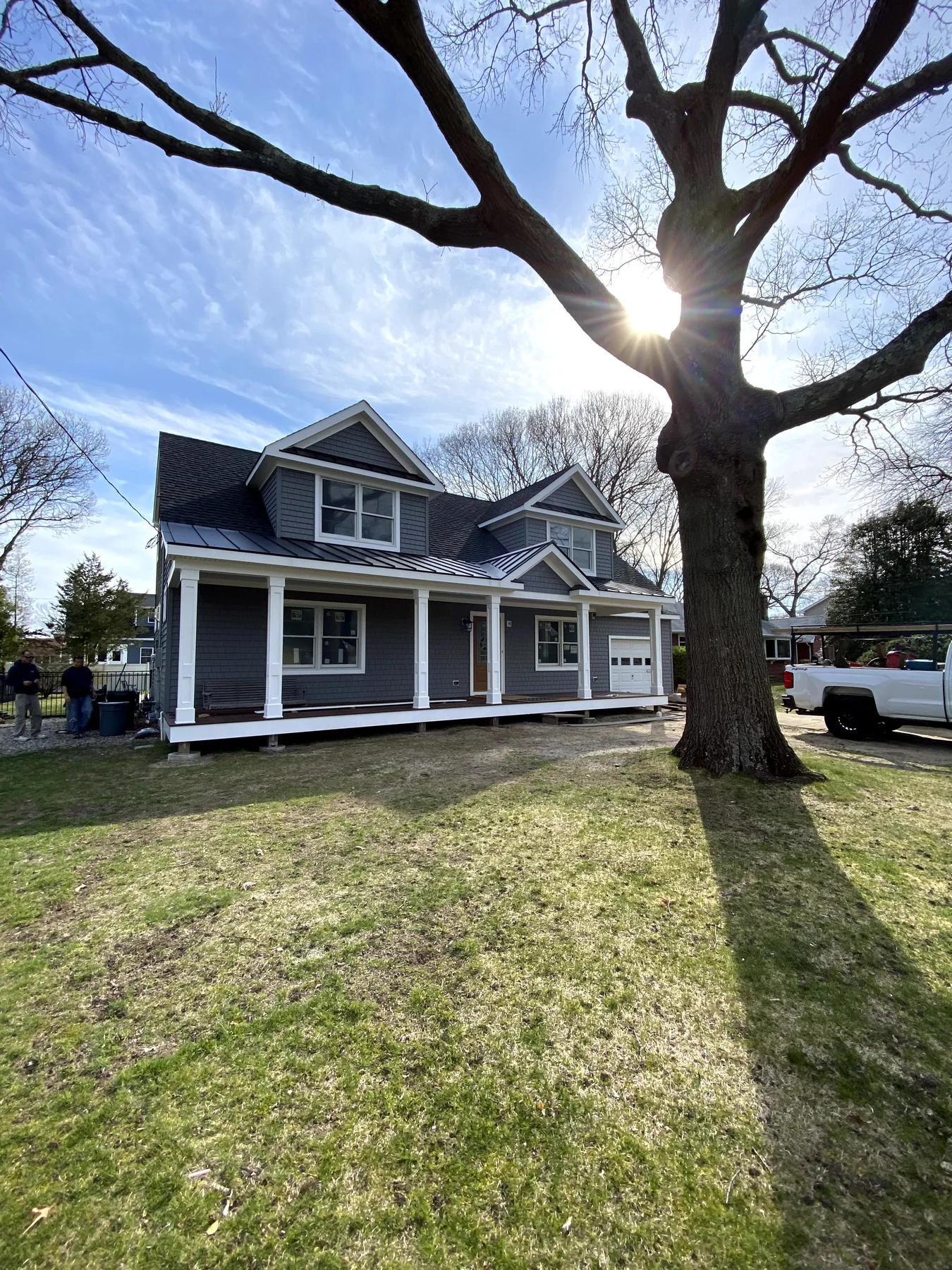 Finished gray custom home under a large oak tree