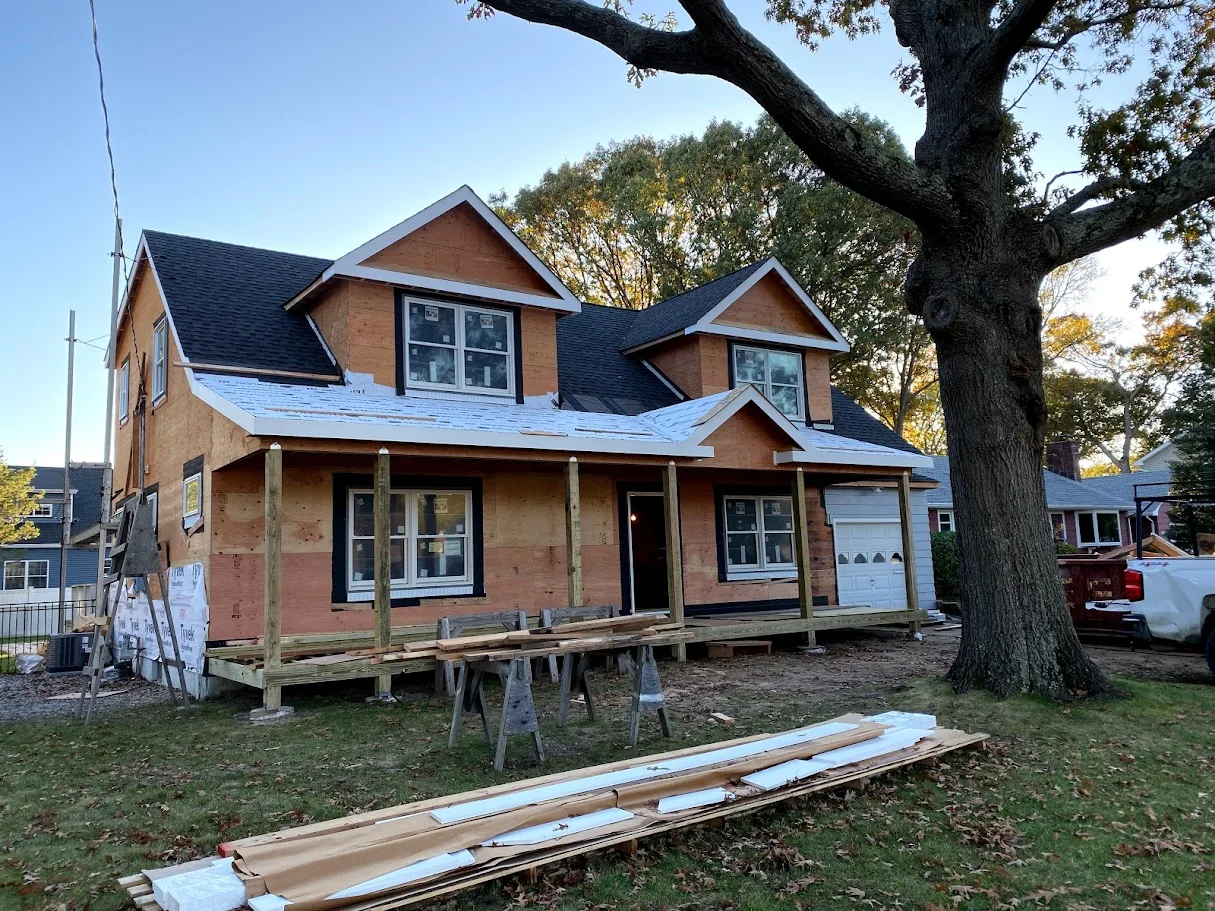 Home exterior sheathed and roofed under a large oak tree before final siding