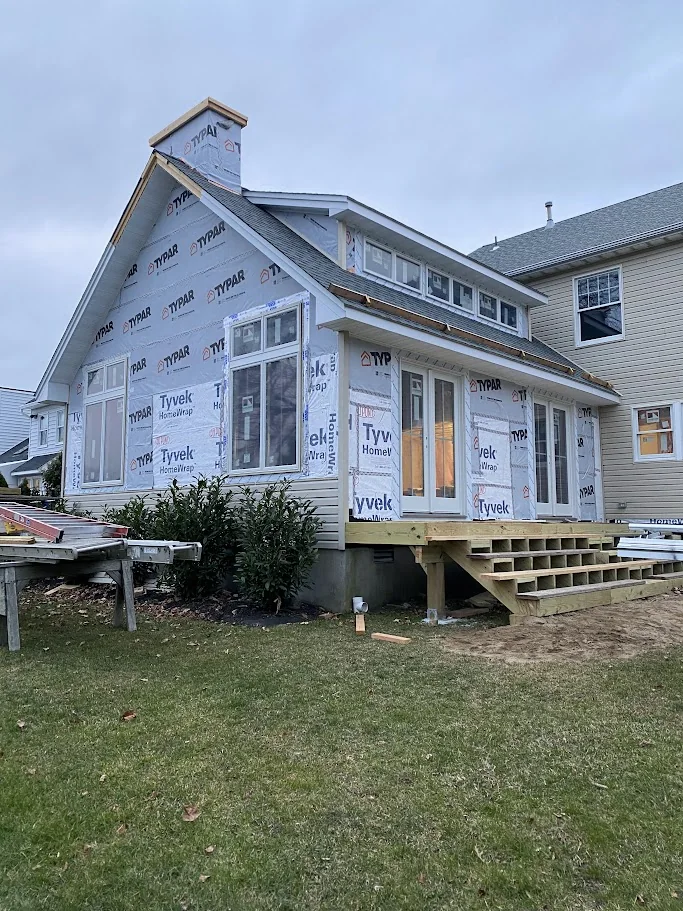 Home addition wrapped in Tyvek with windows and deck framing started